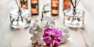 A bouquet of flowers and reed diffusers on a wooden table.