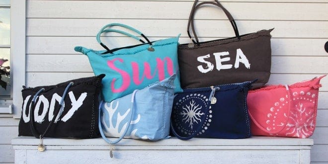 Four tote bags with the words sea, sun, and sand written on them.