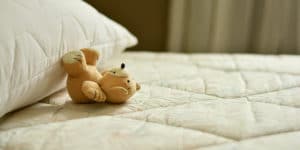 A teddy bear on top of a bed.