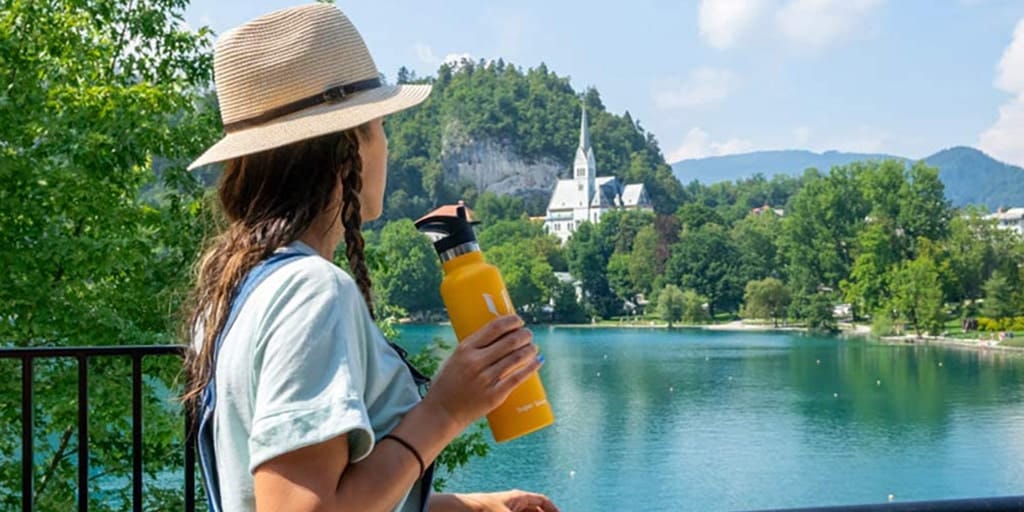 A woman holding a water bottle in front of a lake.