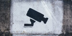 A cctv camera sign on a concrete wall.