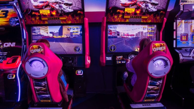 A group of red and black video arcade game machines in a dark room.