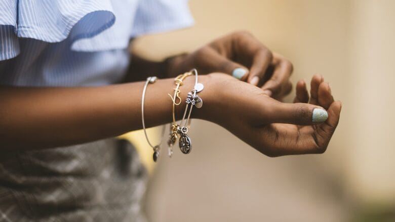 A woman is putting on bracelets on her wrist.