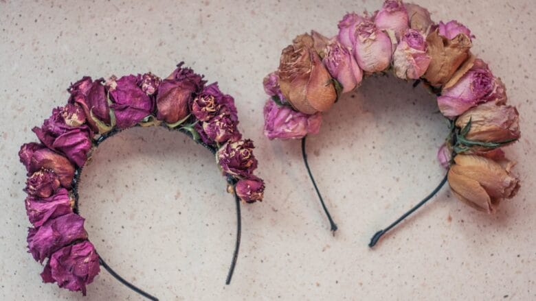 Two pink rose flower headbands on a white table.