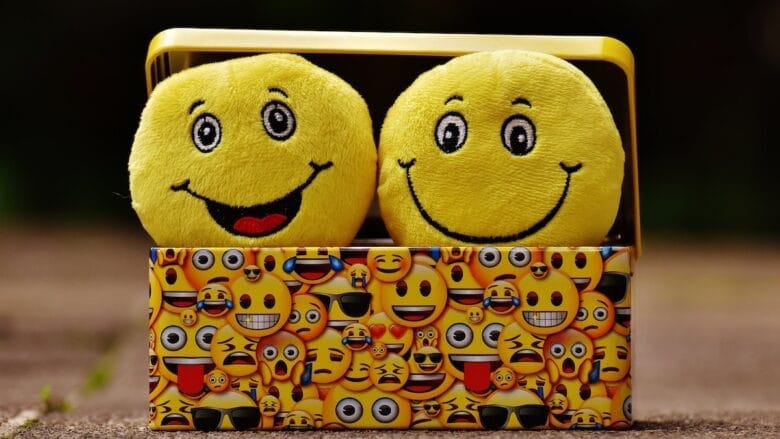 Two yellow smiley emoji faces in a yellow tin box.