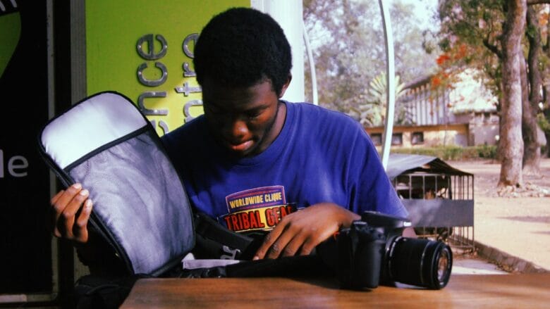 A man sitting at a table with a camera in a bag.