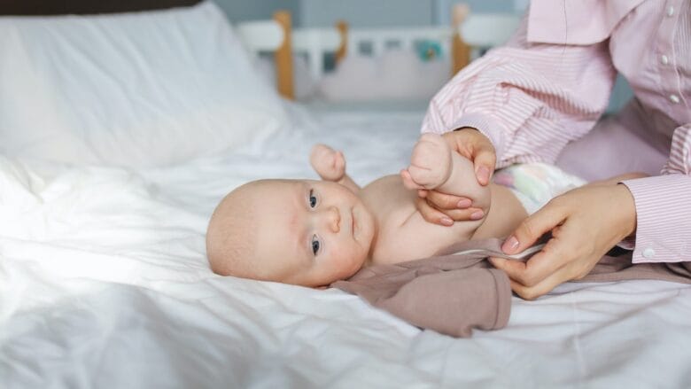 A woman is holding a baby on a bed.