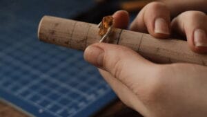 A person cutting a piece of wood into a ring.