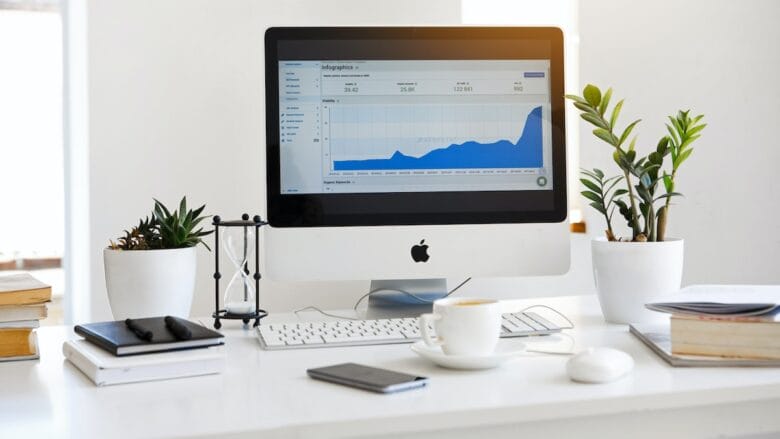 A white desk with a computer and a plant on it.