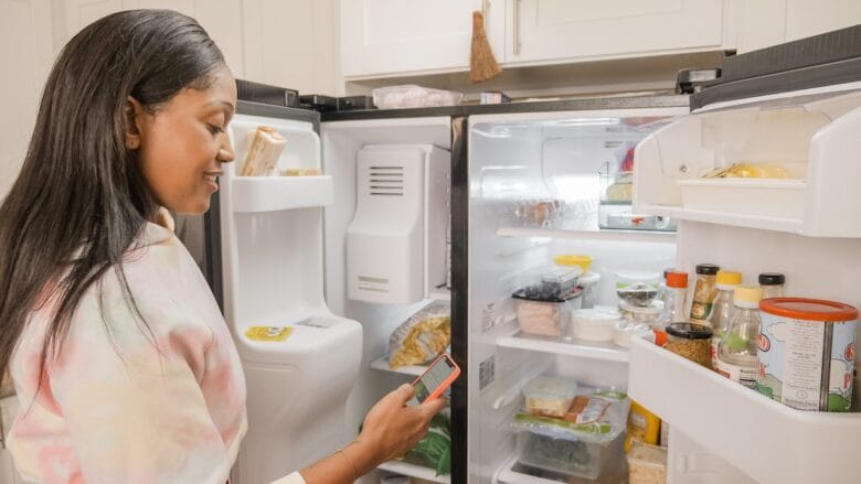 A woman looking at the contents of her refrigerator.
