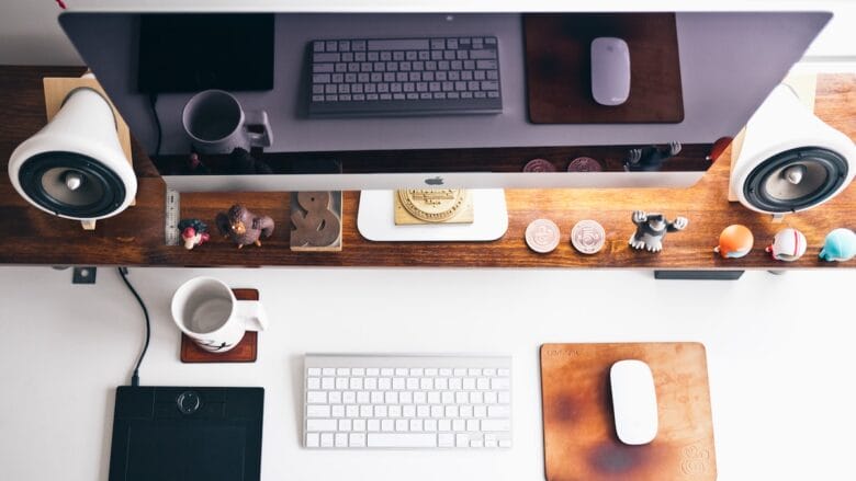 A desk with a monitor, keyboard, mouse and a cup of coffee.