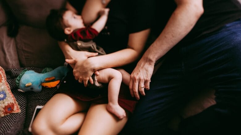 A man and woman holding a baby on a couch.