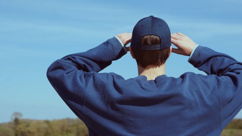 A man in a blue cap is looking at the sky.