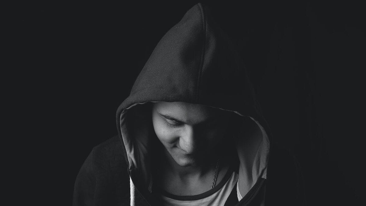 A black and white photo of a man in a hoodie.