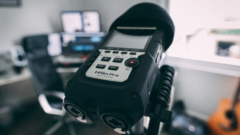 A microphone sits on top of a desk in a recording studio.